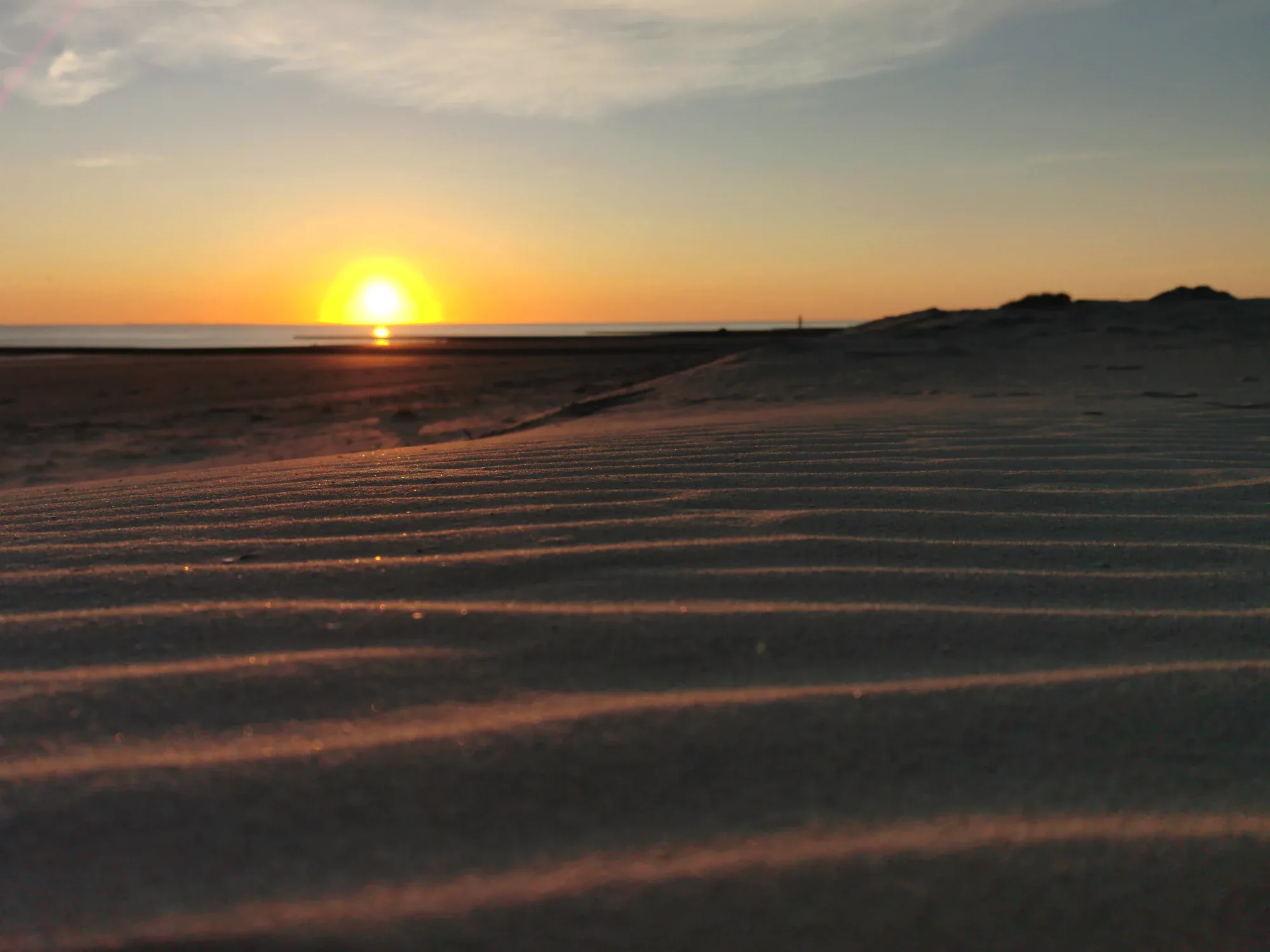 Sonnenuntergang am Borkumer Strand mit Sandrippeln im Vordergrund
